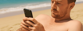 british man on beach checking his mobile phone
